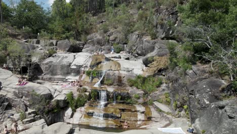 People-relaxing-on-rocks-at-Cascatas-de-Fecha-de-Barjas-in-Peneda-Geres-National-park,-Portugal