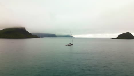 Velero-Anclado-En-Mar-Abierto-Frente-A-La-Costa-De-La-Playa-De-Haukland-Lofoten-Noruega,-órbita-Aérea