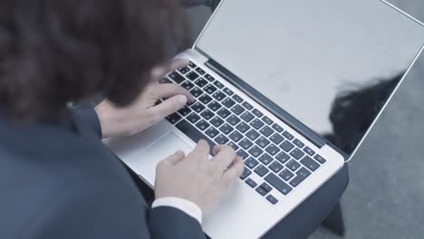 cropped shot of laptop and hands of business woman sitting outside and typing