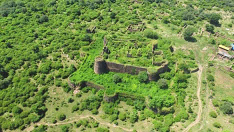 Toma-Aérea-De-Un-Antiguo-Fuerte-O-Castillo-Abandonado-Y-Cubierto-De-Un-Espeso-Bosque-Verde-En-Gwalior-Madhya-Pradesh,-India