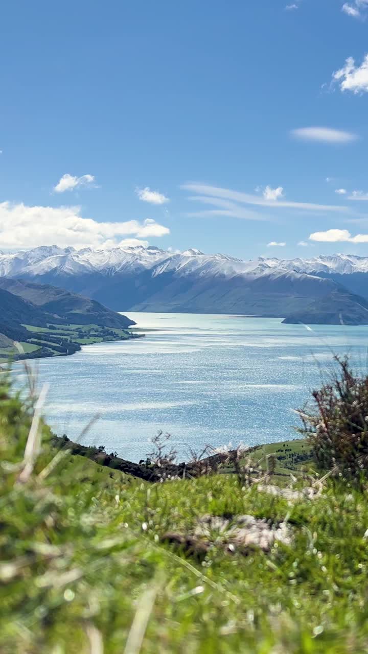 Vista panoramica del Lago Hawea con cime innevate sotto un cielo azzurro brillante