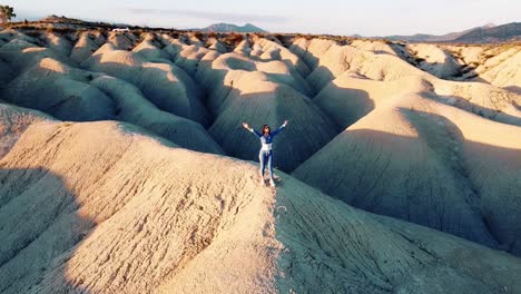 Paisaje-De-Dunas-Desierto-Punto-De-Vista-De-Drones-De-Mujer-Viajando-A-Través-De-Mahoya-En-España-Contra-La-Puesta-De-Sol