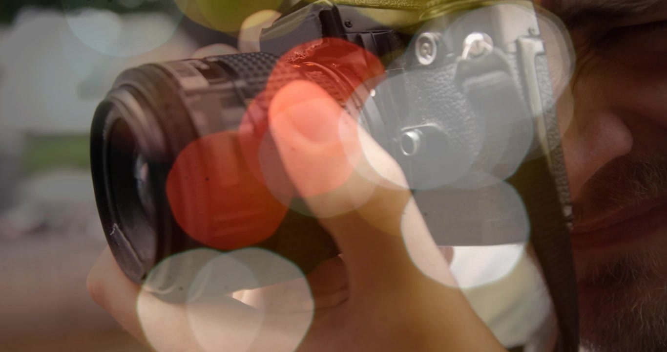 Fotografo che tocca l'obiettivo e ruota l'anello di messa a fuoco rosso mentre solleva una DSLR per un tutorial di fotografia.