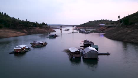 floating houses on a river with bridge