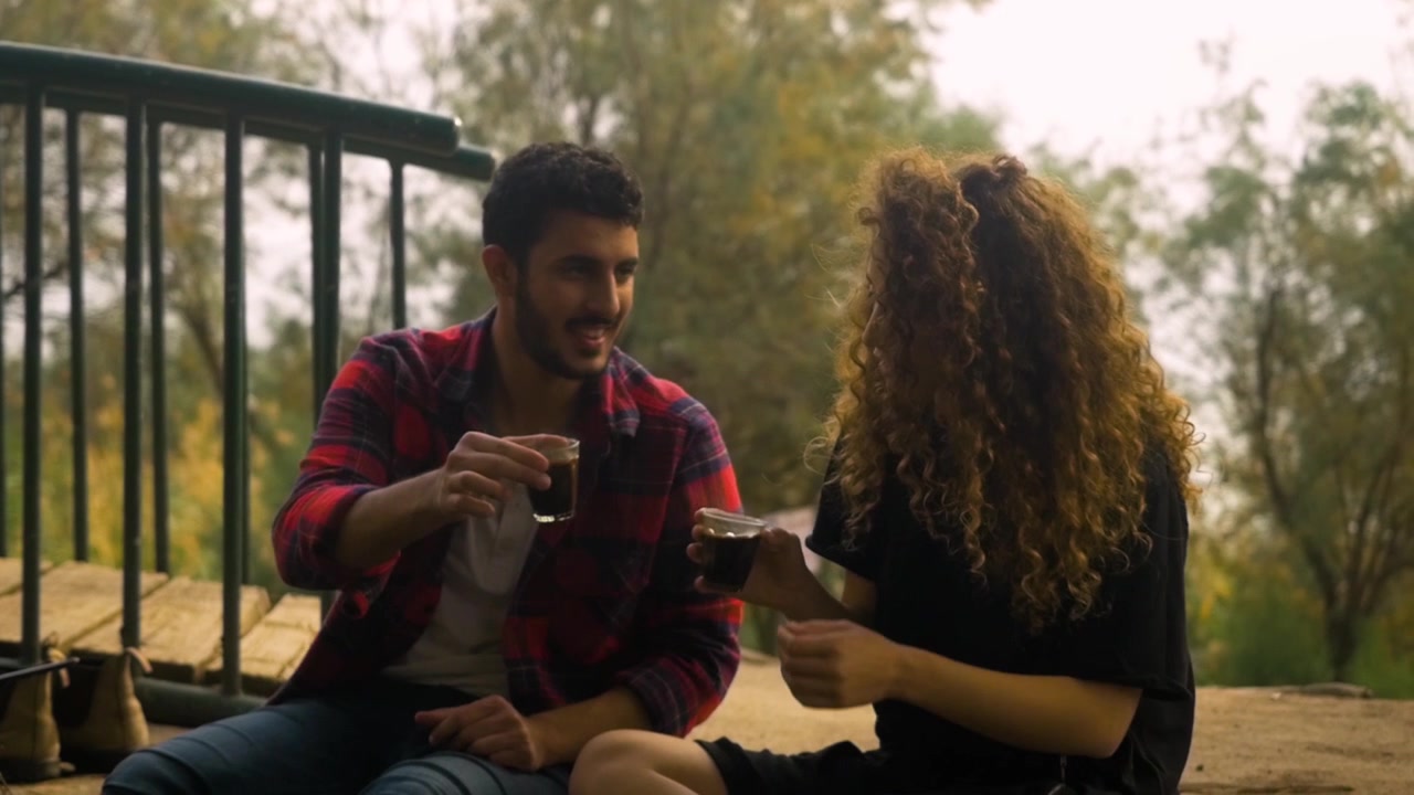 Una coppia carina e innamorata ad un appuntamento che brinda con bicchieri di caffè.