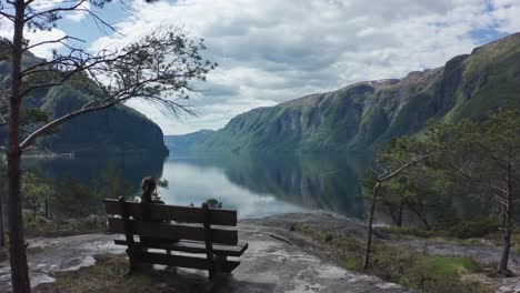 woman relaxing on bench viewing picture perfect sorfjorden fjord norway - stanghelle western norway