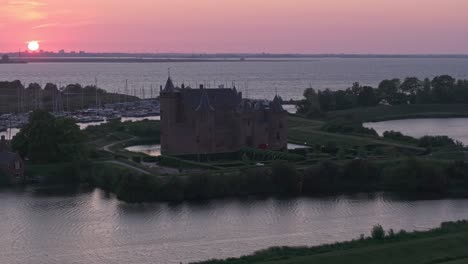 side panning shot of medieval fortress muiderslot castle at muiden with sunset, aerial