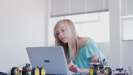 female student building and programing robot vehicle in after school computer coding class