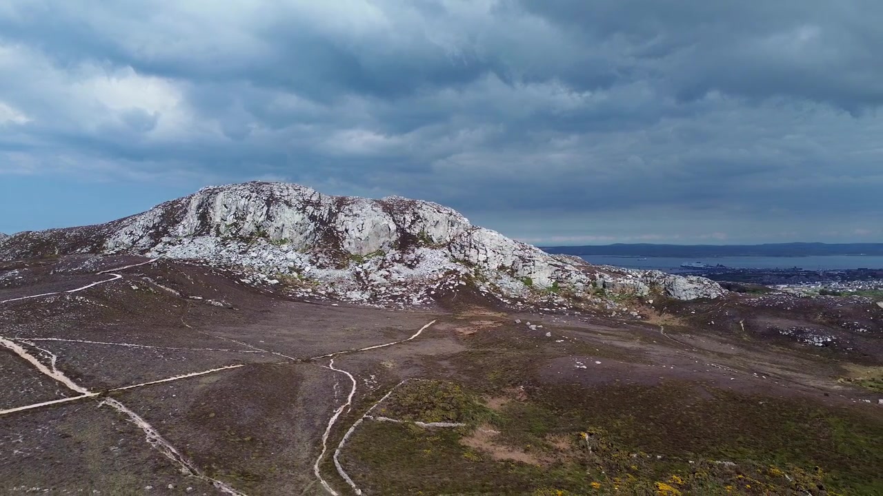 Vista aérea nublada da montanha Holyhead revela trilhas para caminhada e a cordilheira da ilha galesa e paisagem marítima.