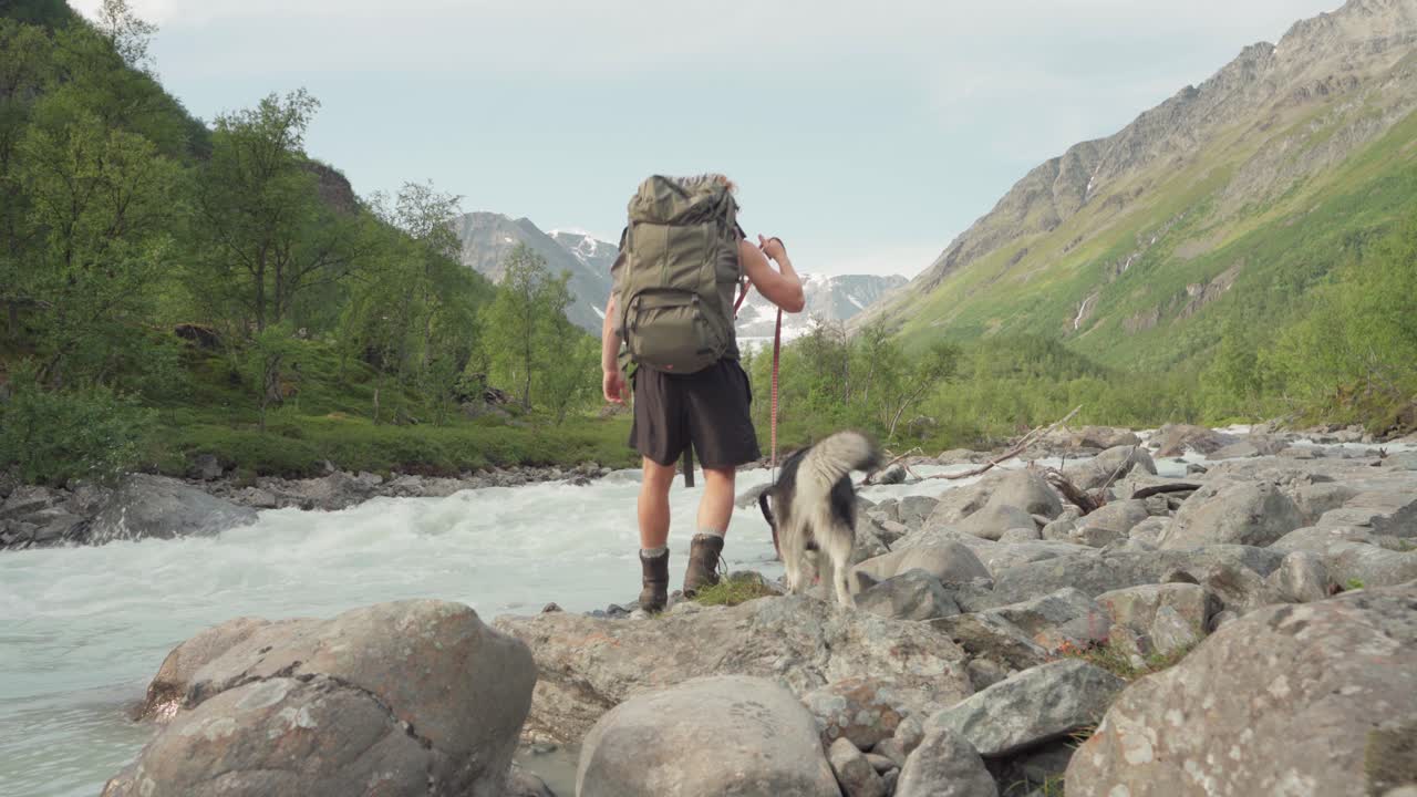 arroyo rápido con excursionista y perro atado en la caminata por la montaña lyngsdalen en noruega