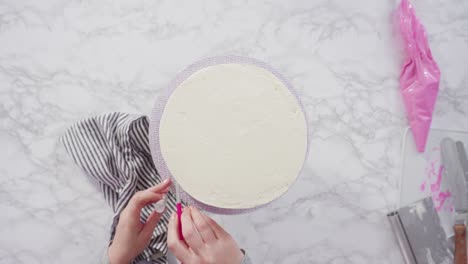 decorating round funfetti cake with pink and white fondant snowflakes.