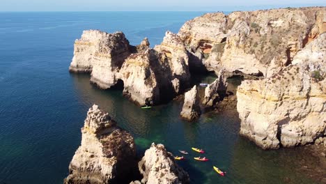 ponta da piedade, lagos, algarve - aerial drone view of kayakking tourists and the coastline with rocky cliffs