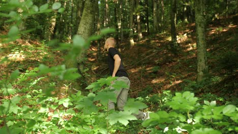 fit young man walking in forest in summer, defocus grom green leaf