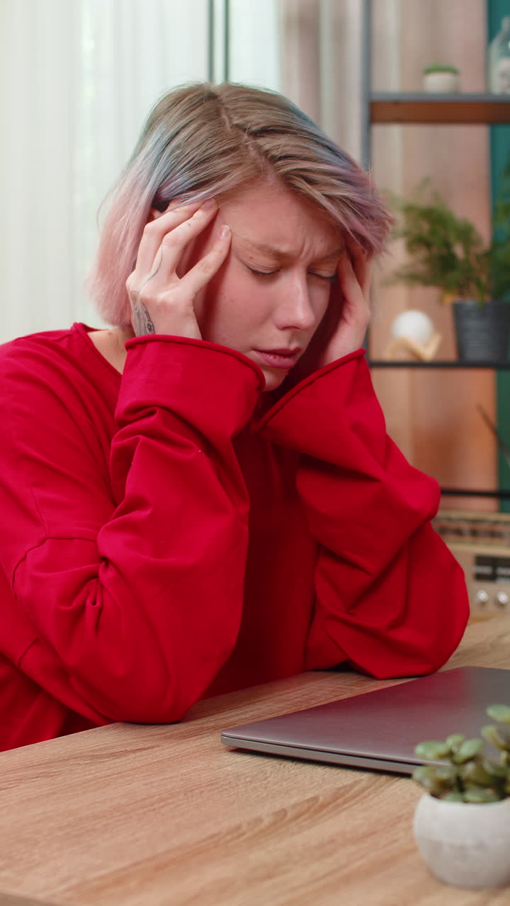 Donna stanca che chiude il laptop, sofferente per il mal di testa dopo una lunga e stressante giornata di lavoro da remoto online
