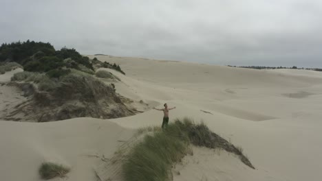 Wide-circular-shot-of-man-standing-on-expansive-sand-dunes