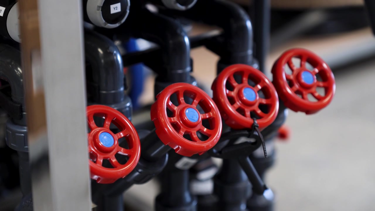 close-up of four red valves with a blue centre, on black water pipes