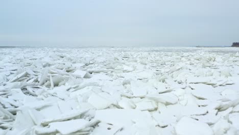 slowly flying forward over snow covered iceburgs in lake