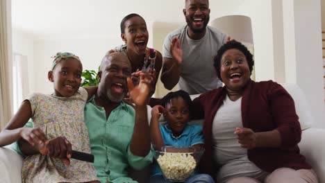 Familia-Afroamericana-De-Tres-Generaciones-Animando-Juntos-Mientras-Ven-Televisión-En-Casa