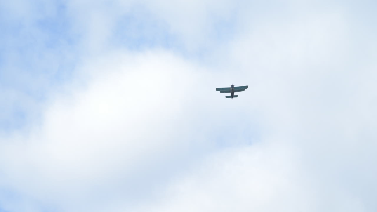 Slow motion low angle view shot of sesquiplane biplane airplane flying across the overcast sky