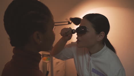 especialista en ojos femeninos hace prueba de visión en niña con lupa