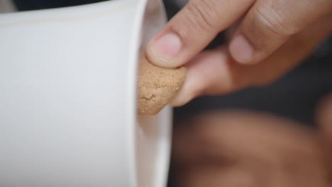hand dipping a cookie into a mug