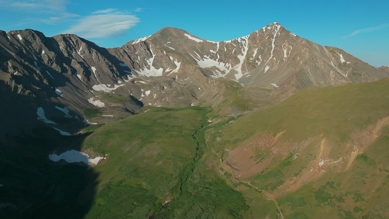 Aerial cinematic drone early morning sunrise hiking trail Grays and Torreys 14er Peaks Rocky Mountains Colorado stunning landscape view mid summer green beautiful snow on top backwards movement
