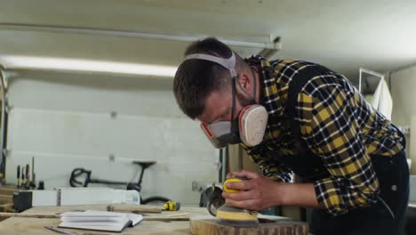 craftsman sanding wood in workshop