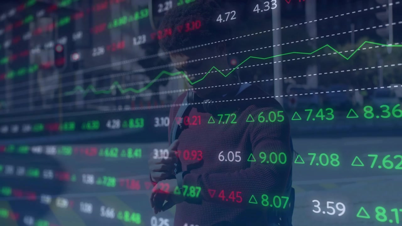 En mann mottar en samtale, holder telefonen og kaster et blikk på rullende markedsdata på en glassflate for å overvåke markedene.