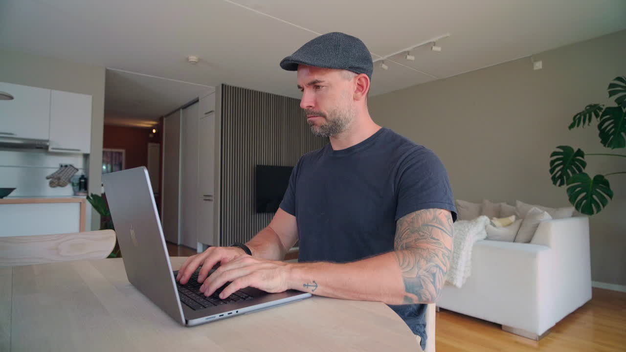 hombre sentado en el escritorio y trabajando desde casa con su computadora portátil - de cerca