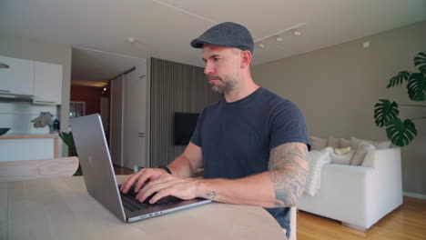 man sitting at desk and working from home with his laptop - close up