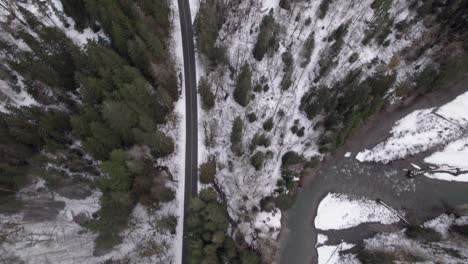 Top-down-shot-of-road-and-river-in-a-winter-wonderland