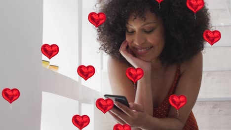 animation of numbers and social media heart icons over biracial woman using smartphone