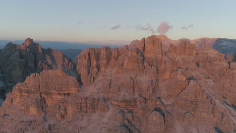 rising aerial view above tre cime south tyrol red sunlit rock formation mountain range shadowy valley