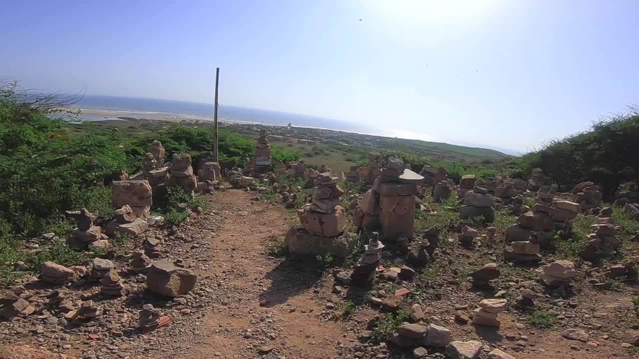 Walking (POV) through many cairns (stacked rocks) on the side of a small mountain while hiking.
