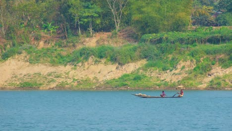 dos hombres asiáticos reman en un pequeño bote tradicional en el río, tiro medio