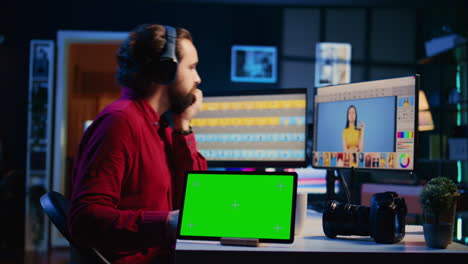 green screen tablet on desk in photography studio next to photo editor color correcting images