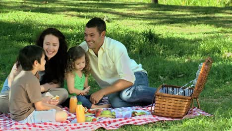 Parents-feasting-at-a-picnic-with-children-on-a-tablecloth