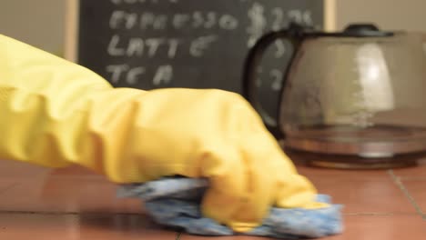 Hands-in-rubber-gloves-cleaning-down-cafe-table-close-up-shot