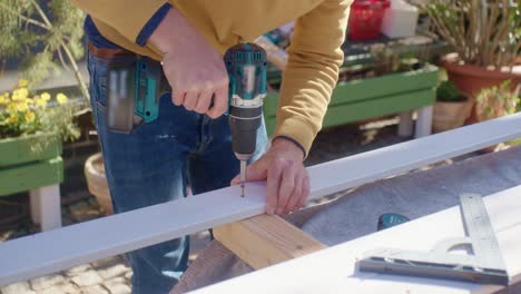 the craftsman holding the wood and drills a screw into it