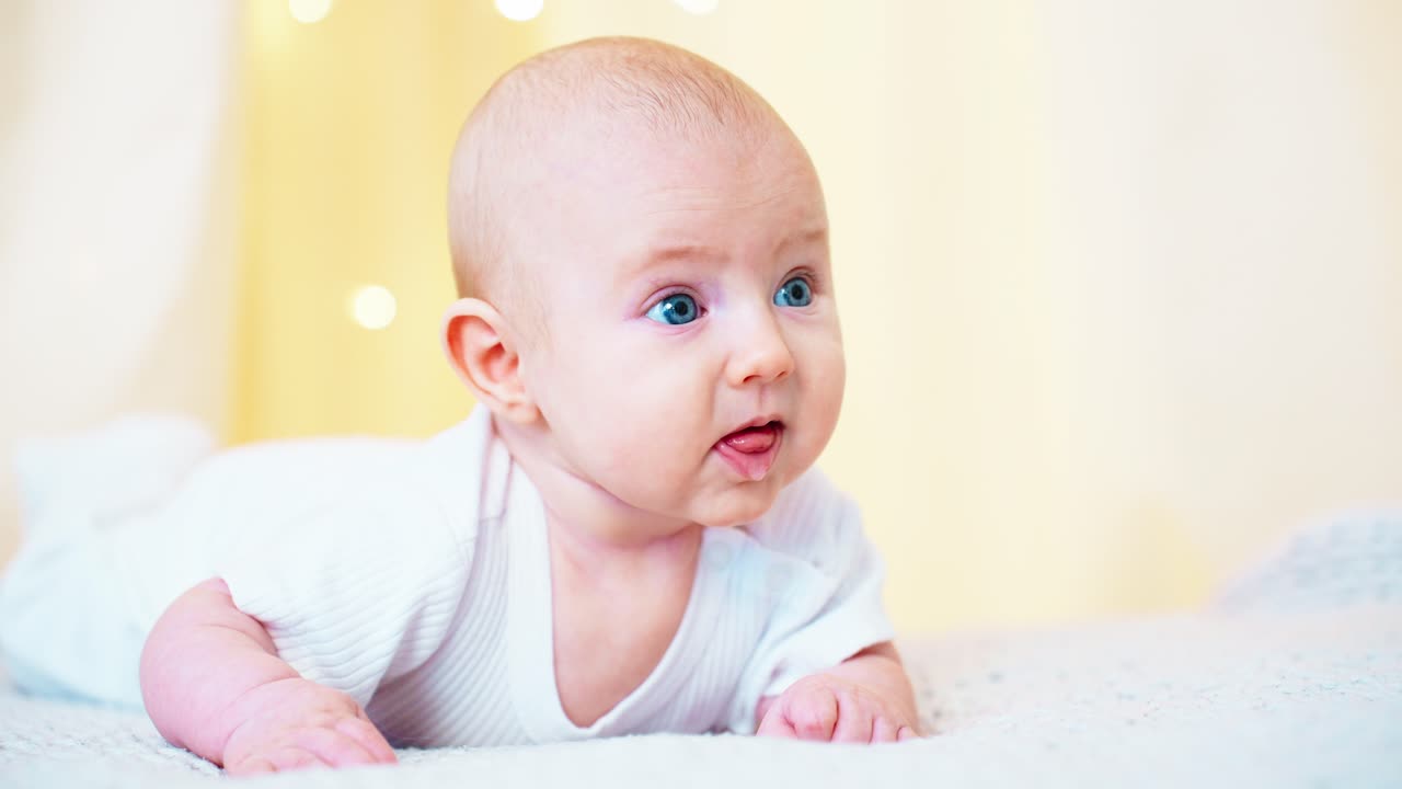 Nærbilde av nydelig baby med blå øyne som ligger på magen