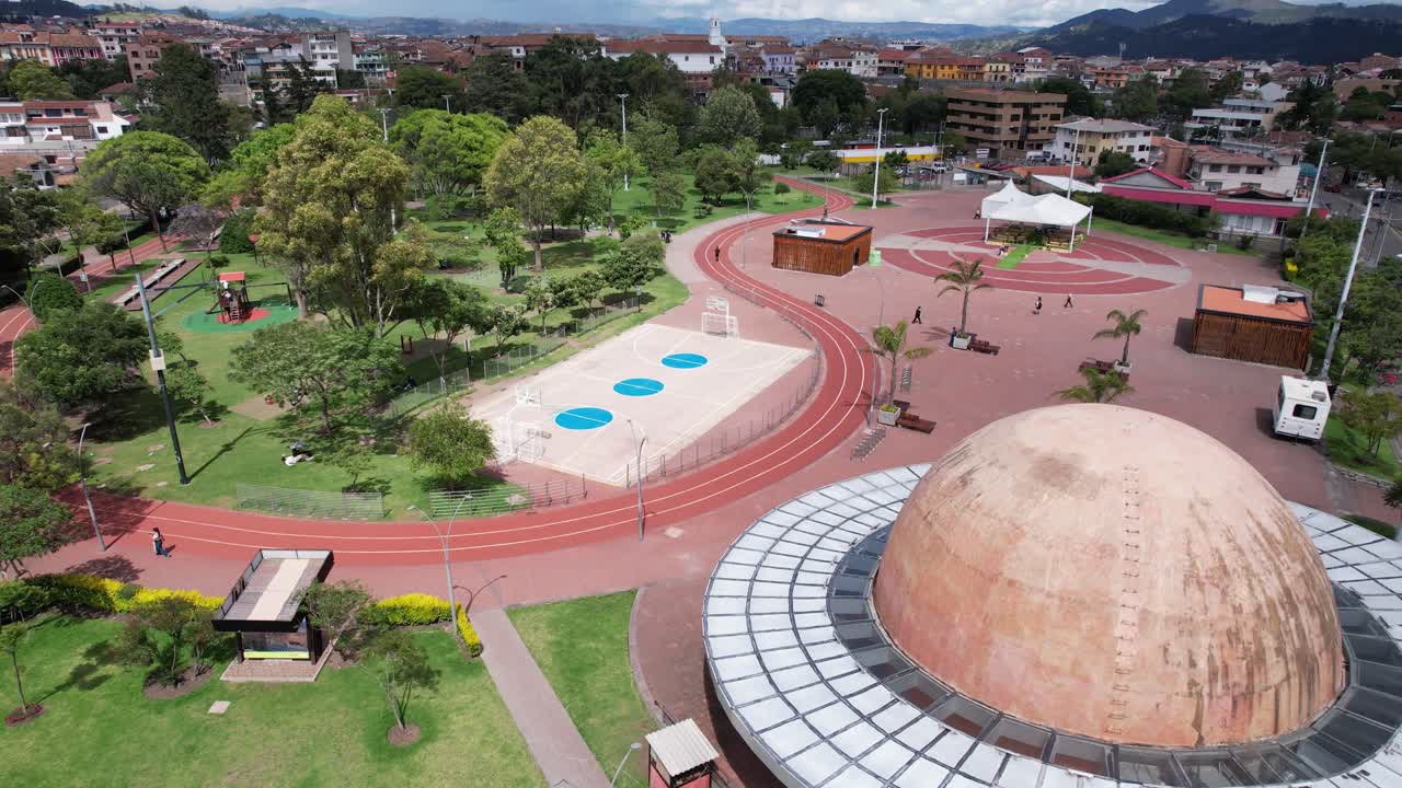 4K drone shot over Parque de la Madre in Cuenca, Ecuador, revealing the cityscape with parks, trees, and buildings in a peaceful urban morning scene