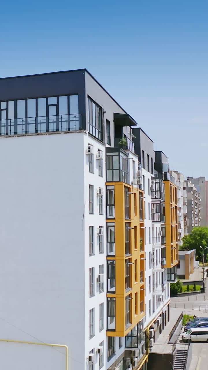 Urban background in sunny daytime. Exterior of a new apartment building. Modern design of high-rise building with large windows and balconies. Vertical video