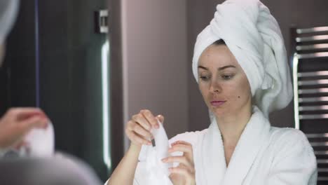 Portrait-of-a-woman-in-bathrobe-putting-white-mask-for-moisturizing