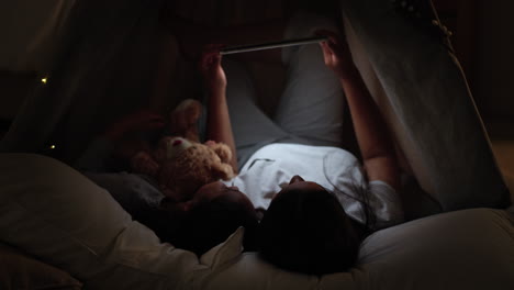 mother and daughter reading together in a tent