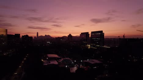 ascending flyover of the araucano park in santiago chile with a view of the city skyline in an orange sunset, las condes district