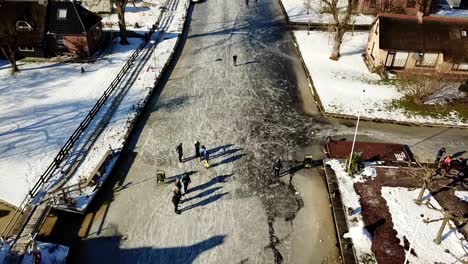 Ice-skating-in-National-park-‘de-weerribben’,-Overijssel,-the-Netherlands-Panning-up-shot-across-a-canal-in-Kalenberg