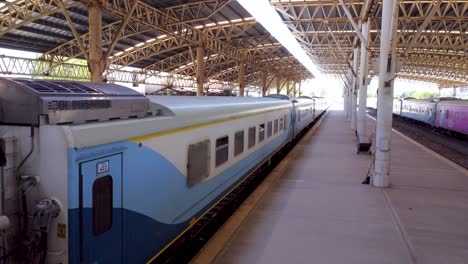 passenger train parking at a station platform, under a large steel roof, at mar del plata station, buenos aires.
