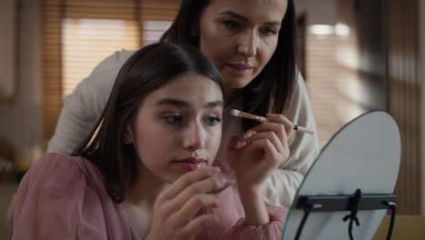 caucasian woman teaching daughter how to do make up for a prom