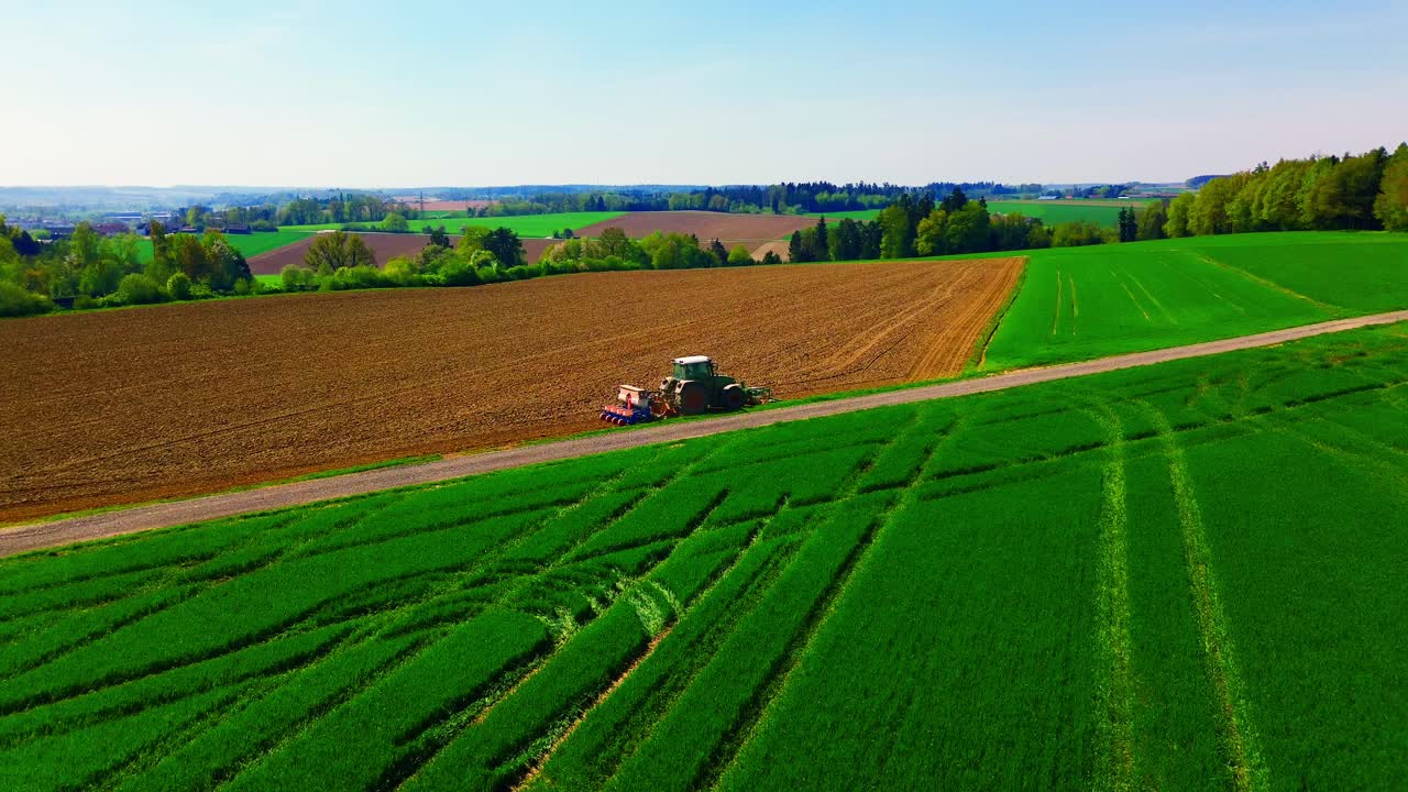 Aerial View of Tractor Working on Green and Brown Farmland in Countryside