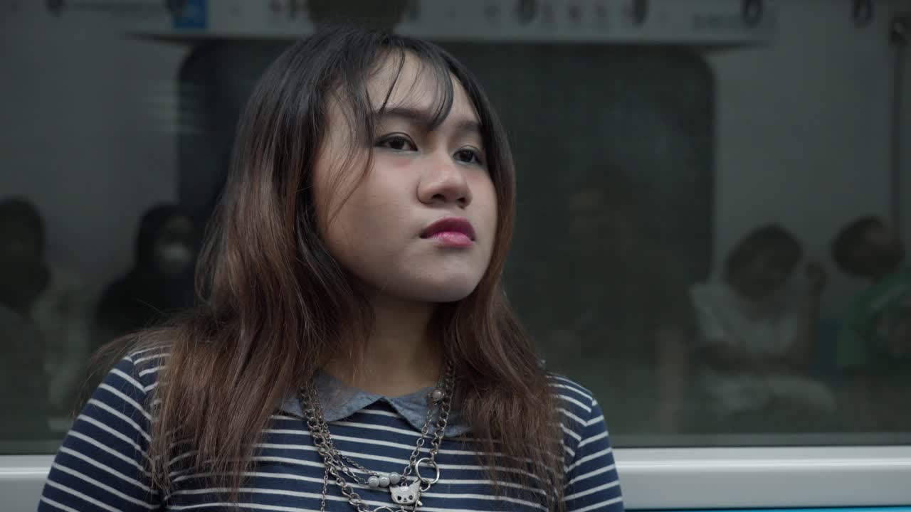 Indonesian girl makes eye contact with camera on a subway ride